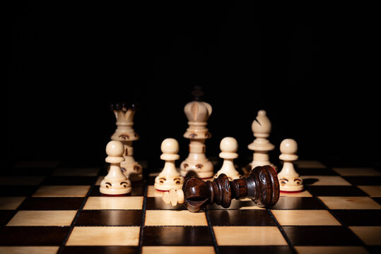 Chess king lying defeated among standing pieces on a board, symbolizing strategy, leadership, victory, failure, decision‑making, competition and business conflict.