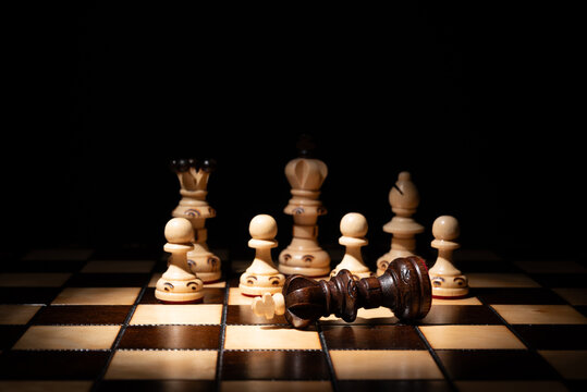 Chess king lying defeated among standing pieces on a board, symbolizing strategy, leadership, victory, failure, decision‑making, competition and business conflict.