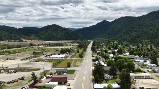 Aerial view capturing the residential area and industrial development in Osburn Idaho small town surrounded by dense forest in spring