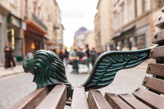 Green iron winged lion bench detail on blurred old town street background in Lviv Ukraine