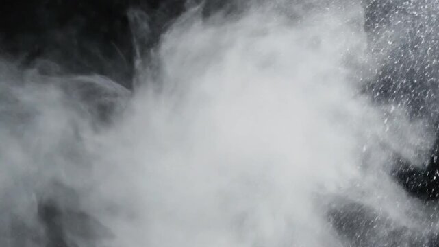 White dust powder released on black background creates interesting patterns and movements in isolated setting