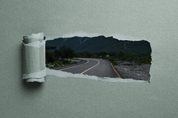 Naklejka premium Mountain road, view through hole in torn pastel green paper
