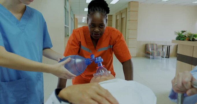 A medical team is urgently moving a patient who has stopped breathing, an emergency patient is performing CPR, a doctor is using an ambu bag.