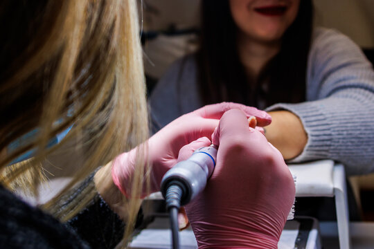 Professional manicurist providing detailed nail care service with a nail drill