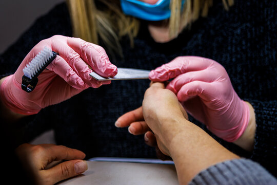 Manicurist working on client nails at beauty salon, offering professional care service