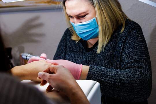 Manicurist providing nail care service with an electric drill at a beauty salon