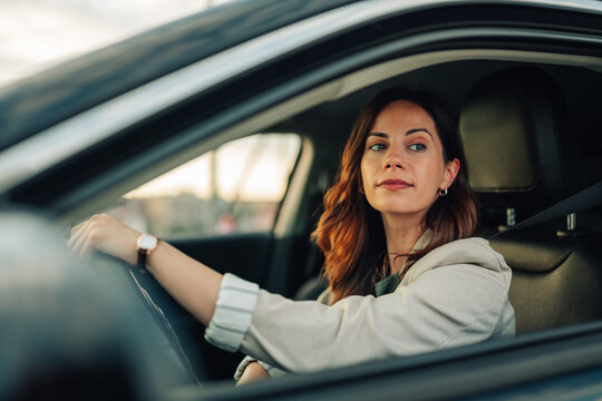 Woman driving her car, focused on the road, commuting in an urban environment during daytime