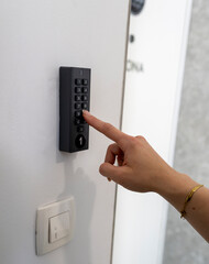 Naklejka premium Close up of hand entering security code on keypad lock for contactless apartment rental guest check in