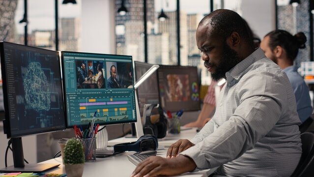Black videographer refining footage with artificial intelligence tools in a high-tech post production agency, Editing software displays wireframe.