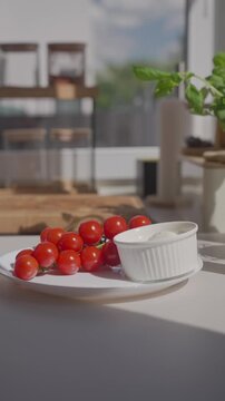Hand arranges cherry tomatoes, olives, mozzarella and garlic on a plate