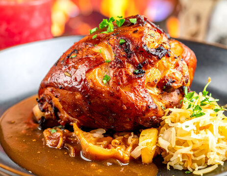 Codillo de cerdo asado crujiente con salsa sobre plato r&uacute;stico alem&aacute;n