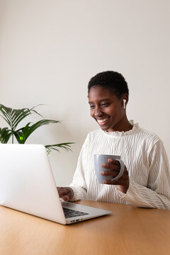 Black woman smiling, working at laptop from home