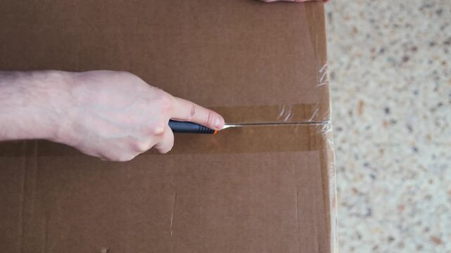 Businessman, man opening big box or cutting with package in warehouse for logistics, return order. Male person, distributor or supplier opening cargo or parcel, courier security distribution