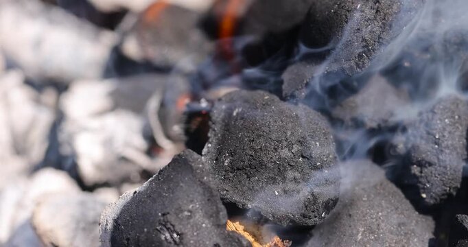 charcoal   and logs burning in a barbecue campfire in the park, details of twigs and charcoal with orange flames and smoke from insufficient air for combustion, fire background