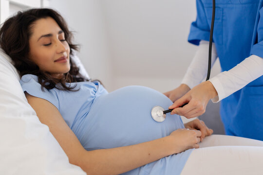 Closeup of nurse using stethoscope on pregnant womans belly during prenatal examination