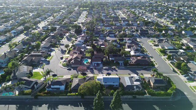 Arterial road frontage near Talbert Ave Bushard St borders dense residential grid in west Fountain Valley, Orange County. Varied roof colors, backyard pools, soft overhead, suburban pattern, CA