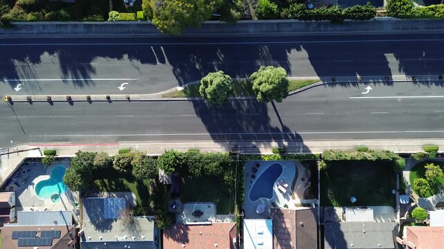 Paired pool parcels along landscaped median near Talbert Ave show aligned homes, consistent lot depths within west Fountain Valley, Orange County. Mixed roofing, long shadows, clipped greenery