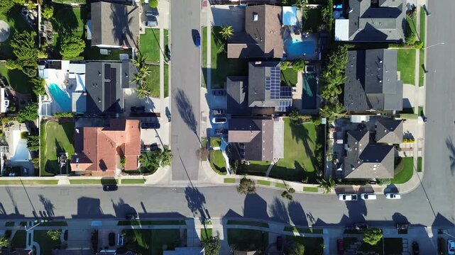 Intersecting neighborhood rows south of Talbert Ave reveal consistent parcels, driveways, landscaped yards west Fountain Valley, Orange County. Varied rooflines, trimmed greenery, aerial layout