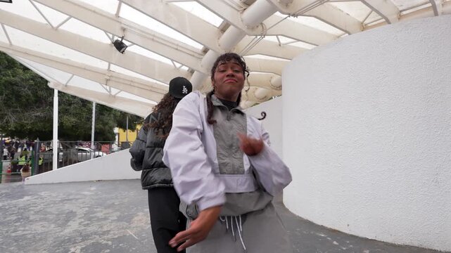 Two stylish young female dancers performing energetic hip hop choreography in a modern urban setting