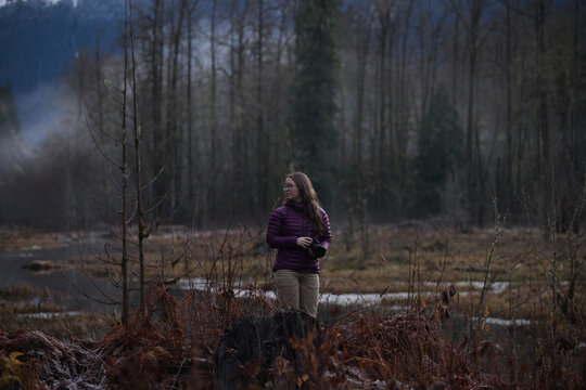 Woman standing in a forest during a cloudy day in early spring