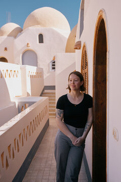 Woman stands by doorway in a building with white walls and round roofs