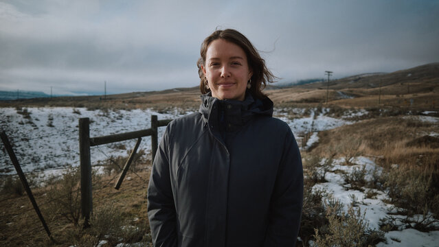 Woman stands in a snowy landscape with mountains in the background