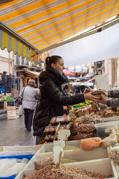 Woman Shopping at a Bustling Outdoor Market in a Historic Town