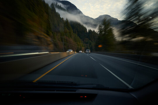 Driving on a winding road through mountains in early evening light