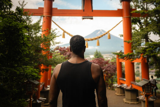 Traveler standing before torii gate with Mount Fuji