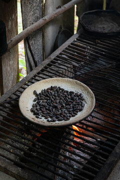 Toasted cacao beans on a clay plate over fire