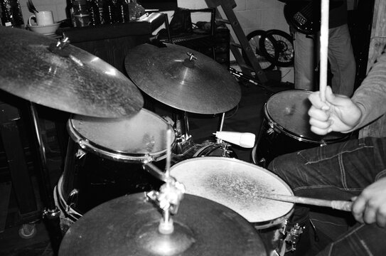 Drummer in DIY garage rehearsal, black and white film energy