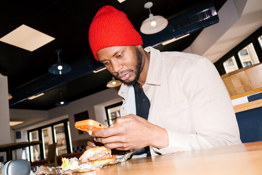 Man capturing restaurant burger food content on smartphone