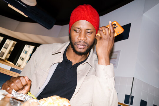 Young man using smartphone messaging at restaurant table