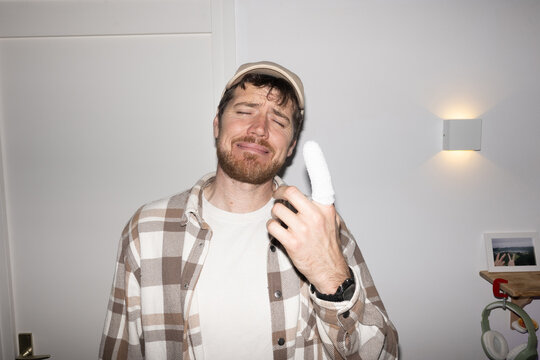 Man With Bandaged Finger Expresses Discomfort 
