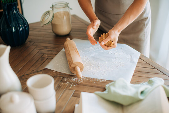 Overhead view of woman shaping dough on floured parchment paper