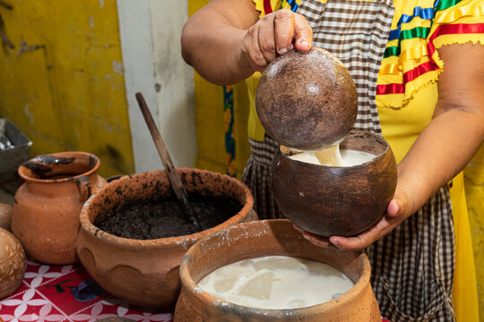 Artisan mixing atole in a gourd bowl.