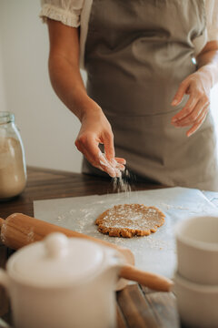 Woman sprinkling flour over dough during baking process