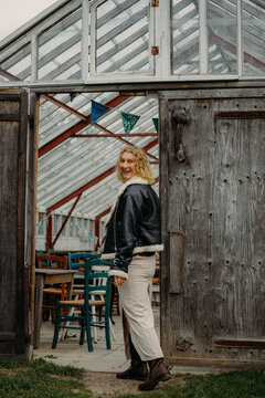 Blond woman smiling entering rustic greenhouse building