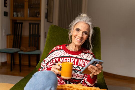 Woman tea and Checks Phone Relaxing at Home