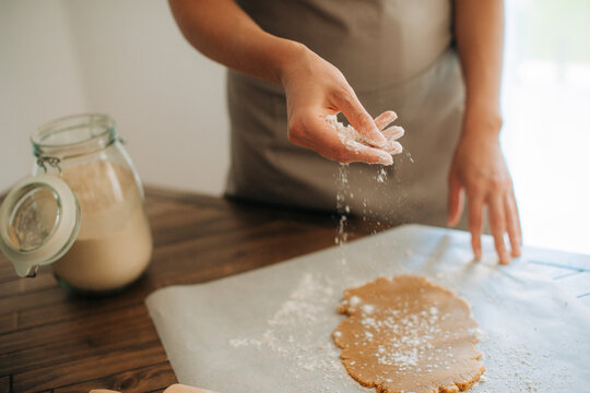 Woman sprinkling flour over dough during baking process