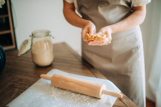 Woman holding fresh dough while baking in cozy home kitchen