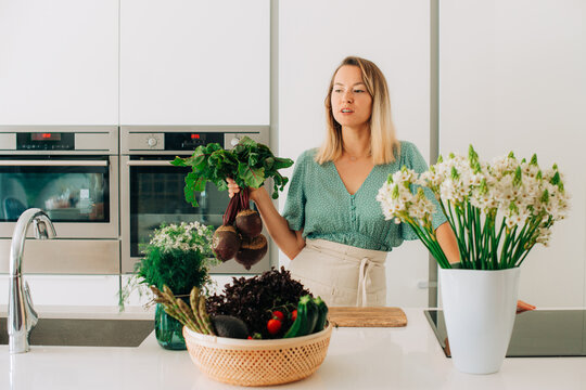 Woman holding fresh beetroots in modern kitchen