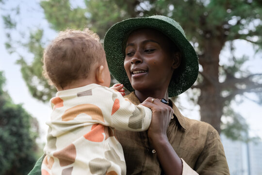 Woman Holds Baby Outdoors Near Trees During Daytime