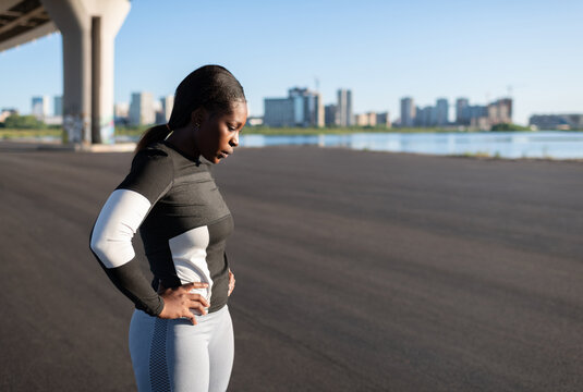 Exhausted black female runner taking pause in workout