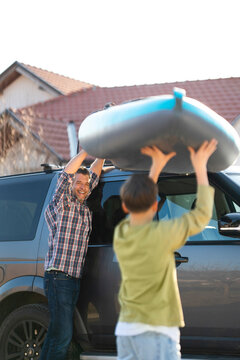 Man and child prepare kayak on vehicle rooftop