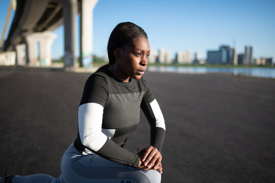 Determined black female athlete lunging on street