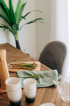 Fresh asparagus on wooden table with herbs and kitchenware in na