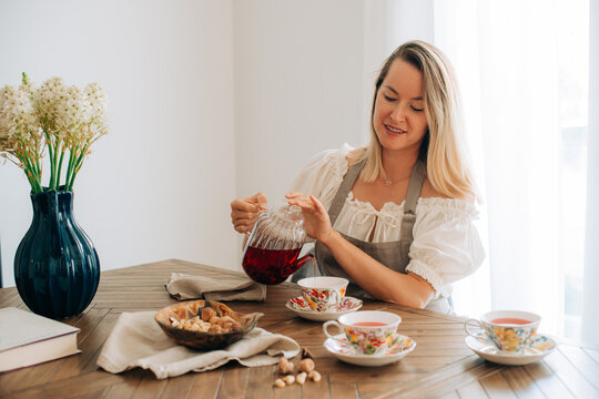 Woman enjoying tea time with snacks in bright cozy interior