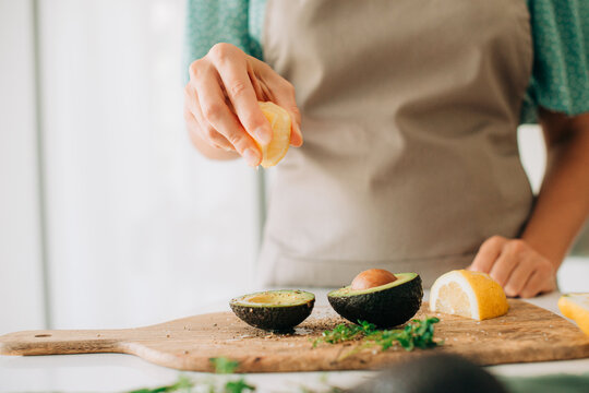Squeezing fresh lemon juice over avocado halves on cutting board