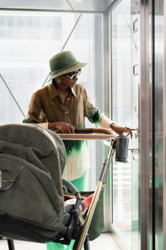 Woman With Stroller Presses Elevator Button in Modern Building